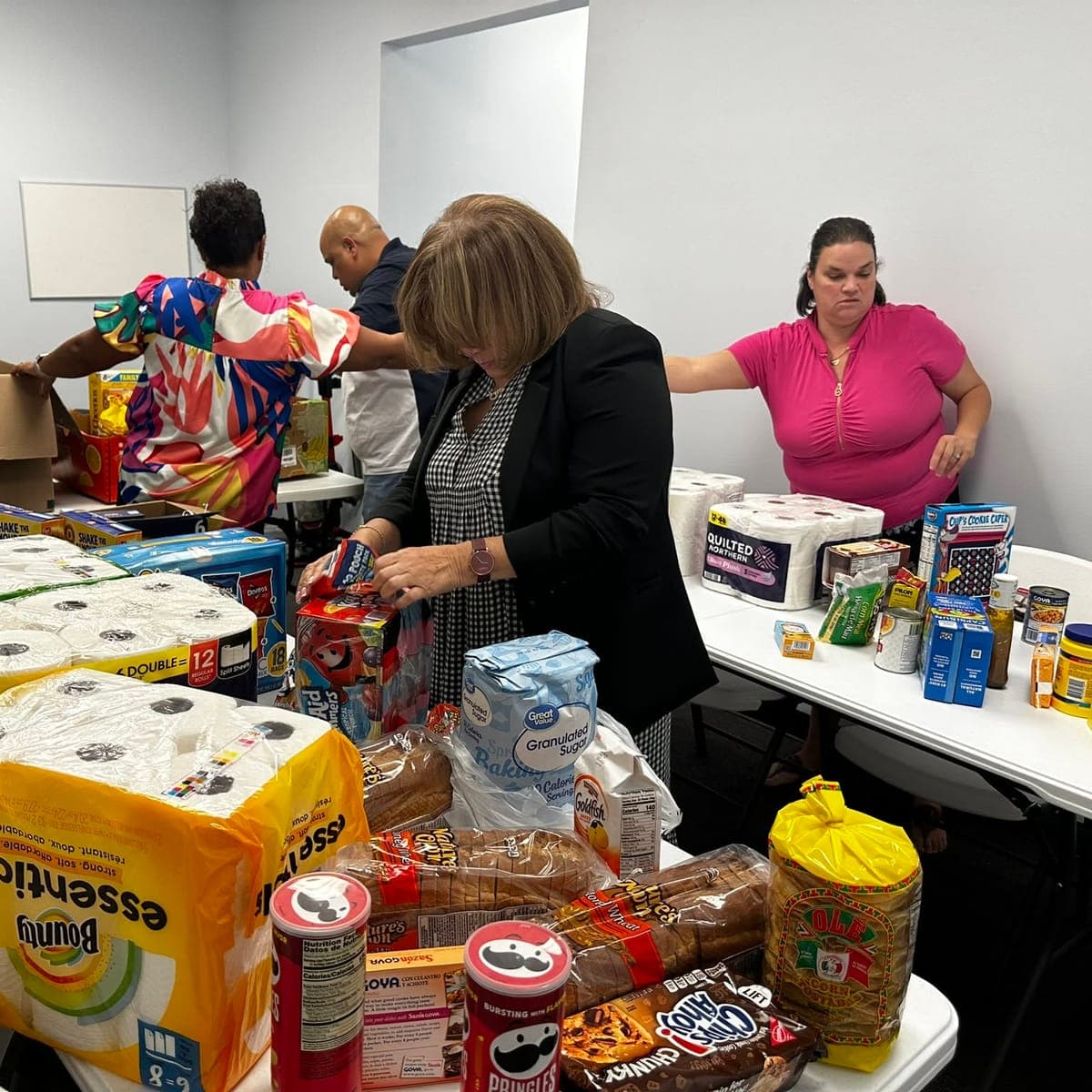 Voluntarios de la iglesia armando despensas con alimentos y productos de primera necesidad sobre las mesas