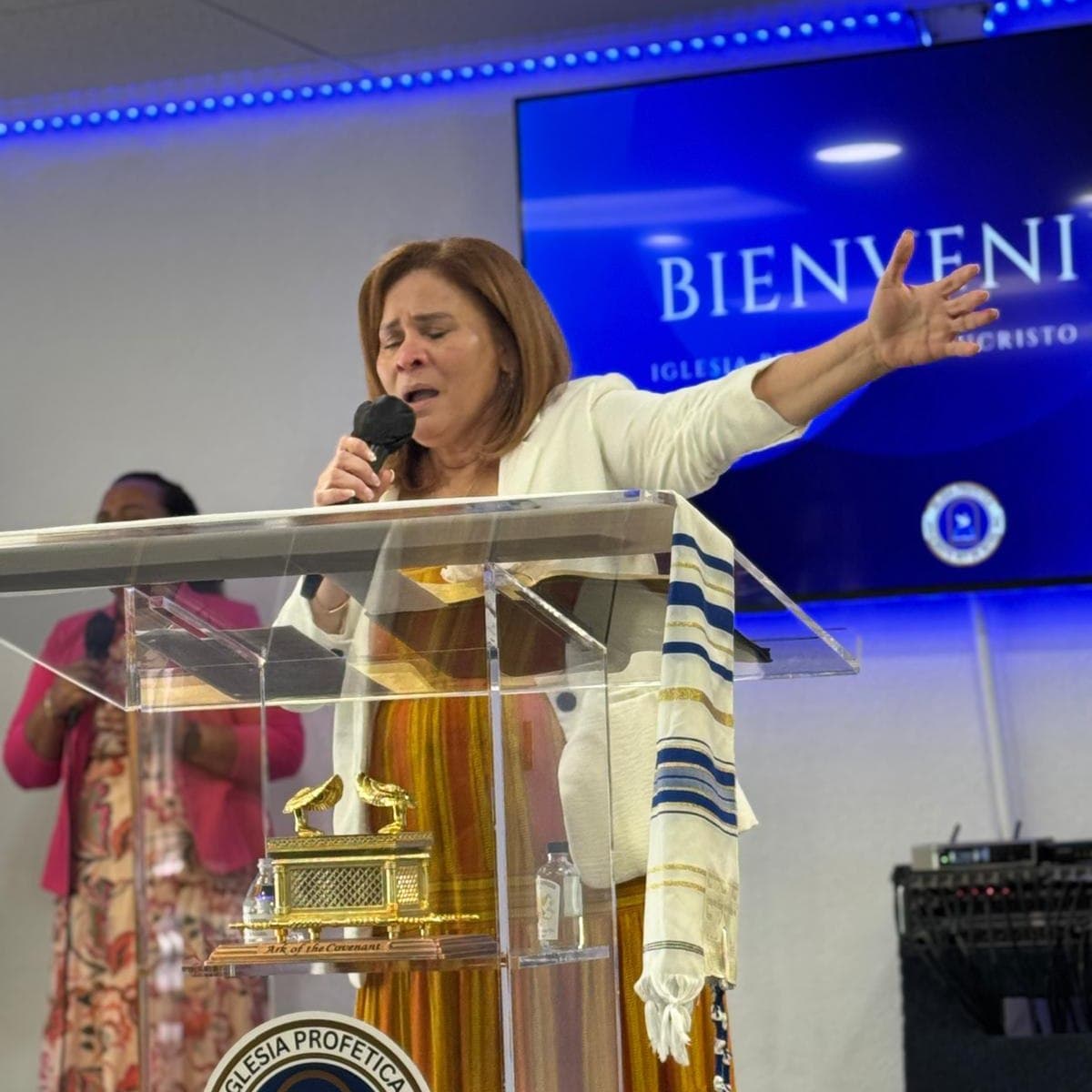 Pastora orando con el brazo extendido durante el servicio
