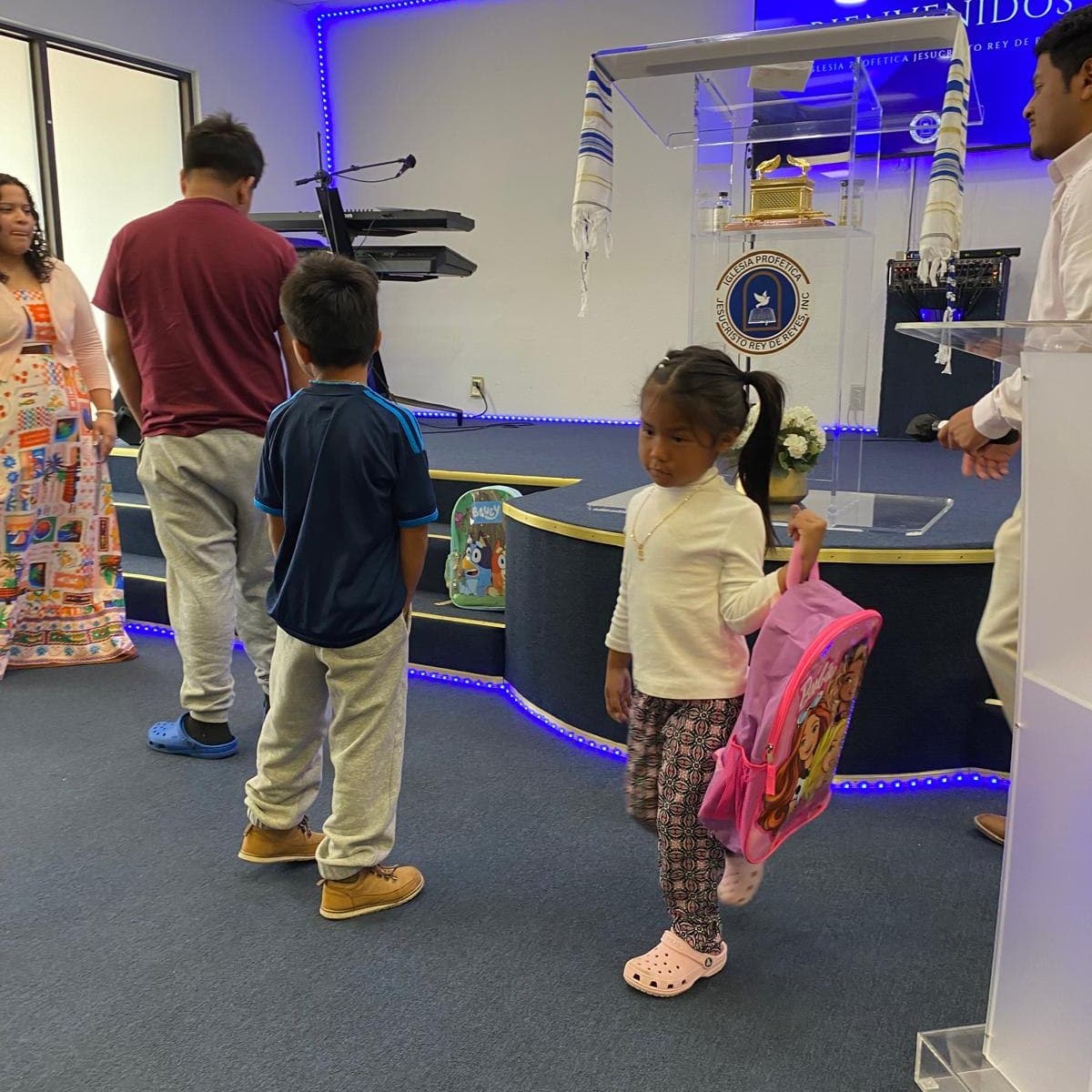 Niños de la iglesia con sus mochilas nuevas frente al altar