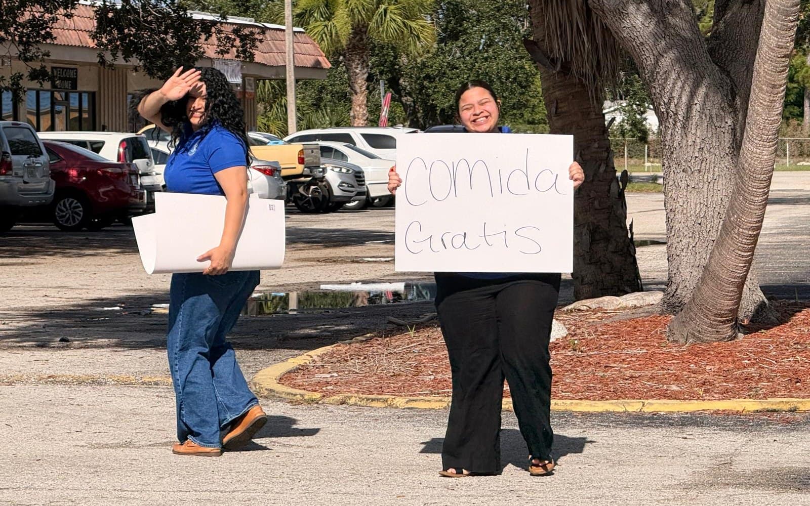 Voluntarias invitando con carteles de comida gratis frente a la iglesia
